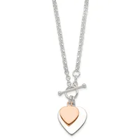 Silver chain necklace with toggle clasp featuring two stacked heart pendants, one rose gold and one silver, hanging together.