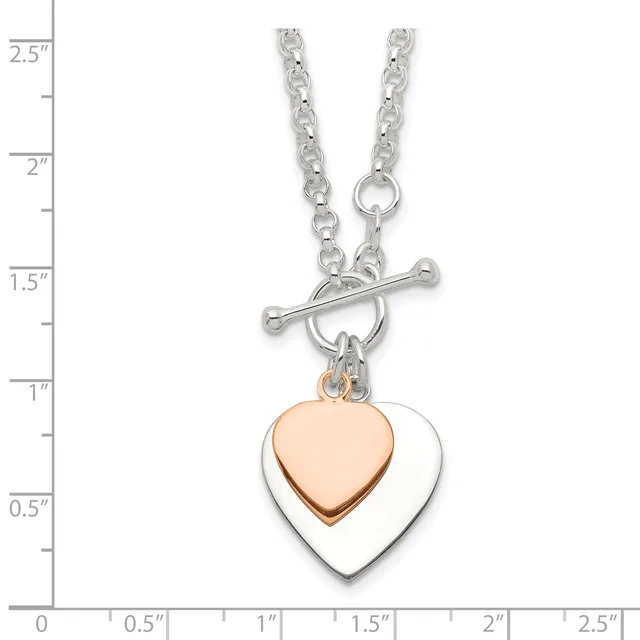 Silver chain necklace with toggle clasp featuring two nested heart pendants, one rose gold and one silver, displayed against a measurement scale.