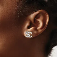 A silver stud earring with an interlocking double C design worn on the earlobe of a person with brown skin.