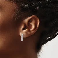 A person wearing a rectangular silver bar earring with a small hallmark, shown from the side profile against a neutral background.