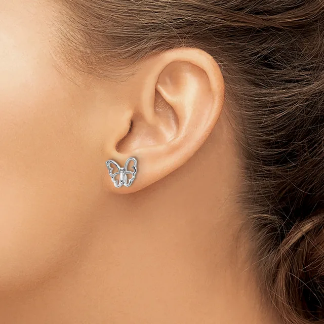 A person wearing a small silver butterfly stud earring in their earlobe, shown in profile view.