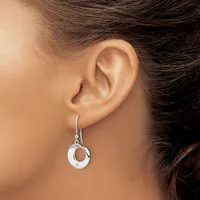 A silver drop earring with a circular open design hangs from a hook, worn on a person's earlobe.