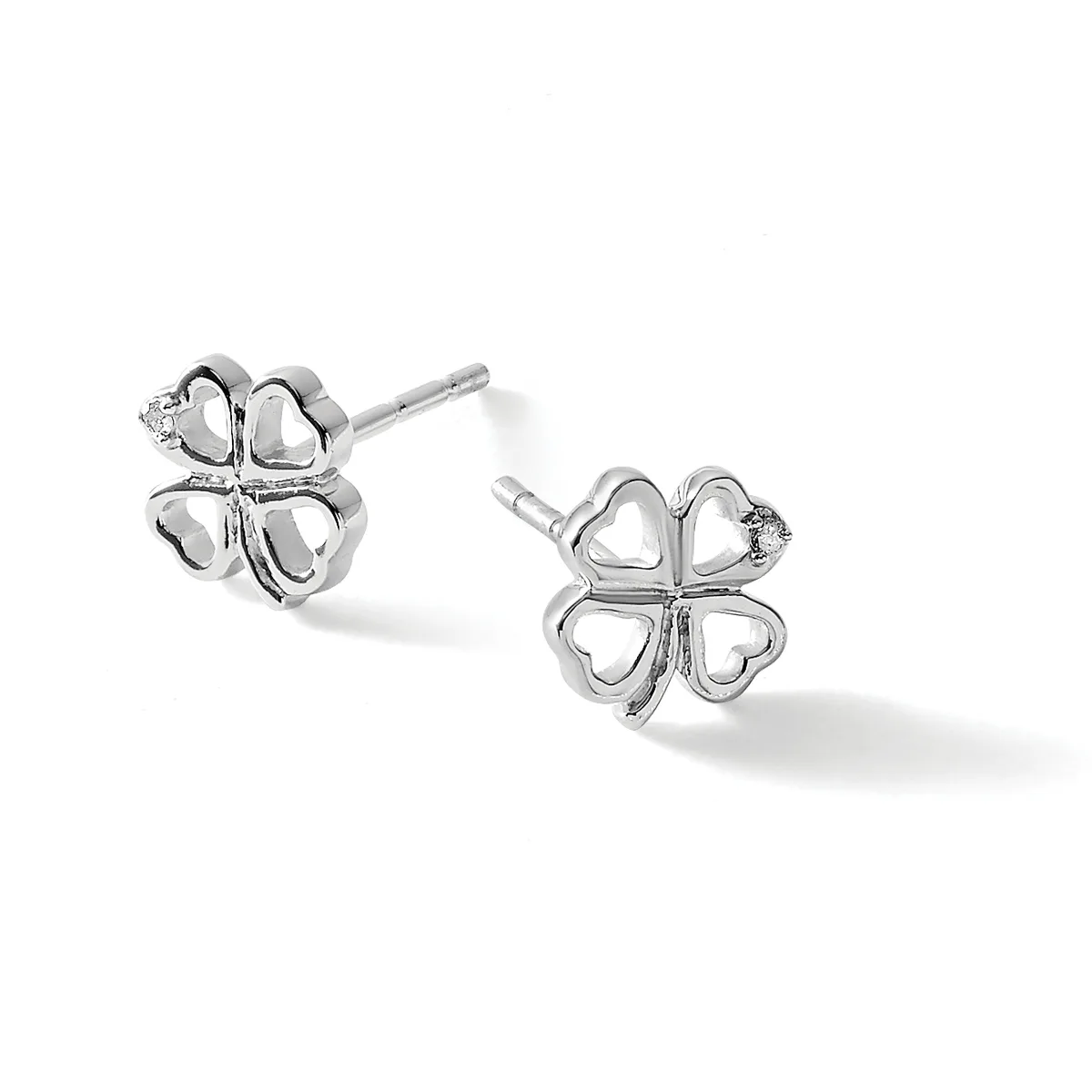 A pair of silver four-leaf clover stud earrings with hollow heart-shaped petals and small diamond accents, shown from two angles on a white background.