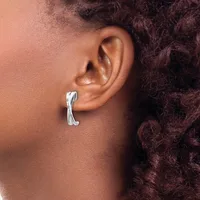 A person wearing a silver curved cuff earring in their pierced earlobe, shown in profile view against their shoulder and dark curly hair.