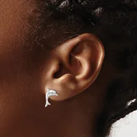 A silver crescent-shaped earring worn in a person's earlobe, shown in profile against their brown skin tone.