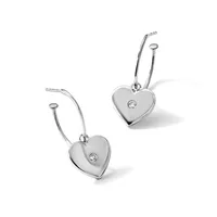A pair of silver heart-shaped drop earrings with curved wire hooks, each heart featuring a small diamond set off-center.