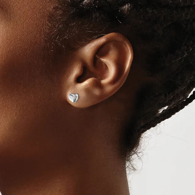 A person with dark hair and brown skin wearing a small silver heart-shaped stud earring in their earlobe, shown in profile against a white background.