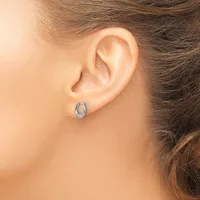 A person wearing small silver hoop earrings with a textured surface, shown from the side view of their ear and neck.