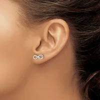 A person wearing a small silver infinity symbol stud earring in their earlobe, shown from the side profile view.