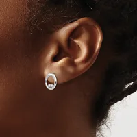 A close-up view of a person's ear wearing a small oval silver hoop earring with a decorative center detail.