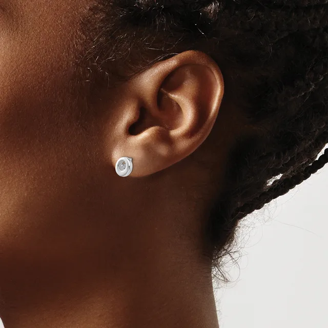 A person wearing a small oval silver stud earring with a blue stone or enamel center, shown from the side view of their ear and neck.