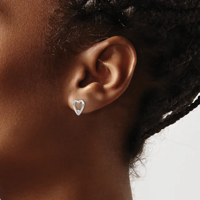A person wearing small silver heart-shaped stud earrings, shown in profile from the side of their head and neck.