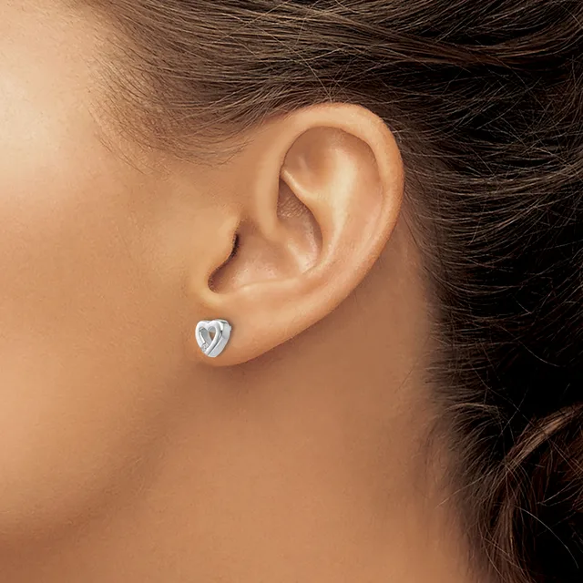 A person wearing a small heart-shaped silver stud earring in their earlobe, shown in profile view.