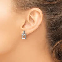 A woman wearing a rectangular pendant earring with a blue gemstone accent on the top bail, displayed on her earlobe.
