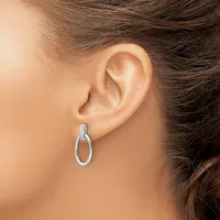A woman wearing a small silver oval hoop earring with a textured top section, shown from the side view of her ear and neck.