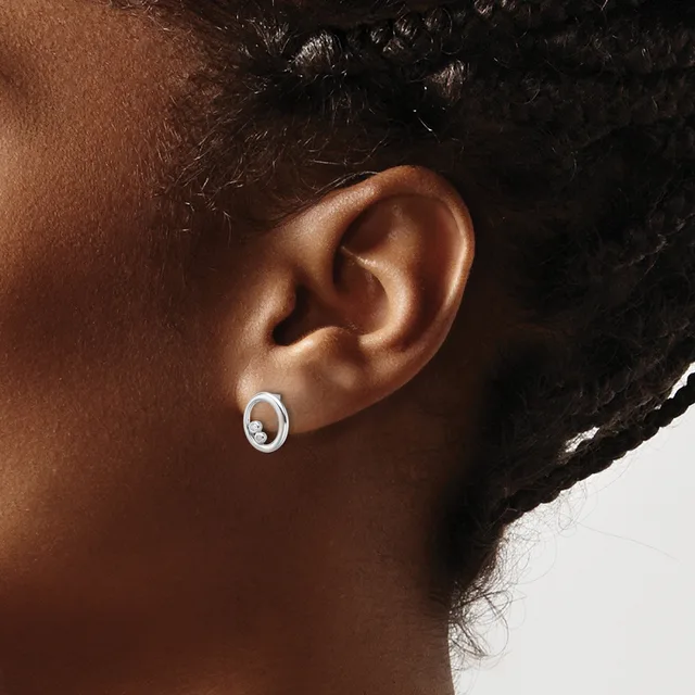 A person wearing small oval silver hoop earrings with a white stone or pearl in the center, shown from a side profile view.