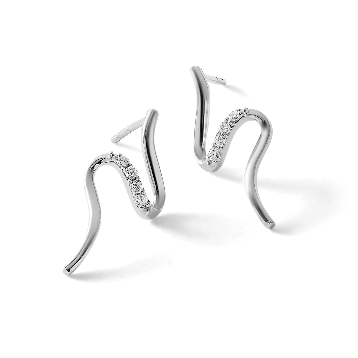 Pair of curved silver hoop earrings with diamond pave detailing on one side of each hoop, shown from a three-quarter view against a white background.
