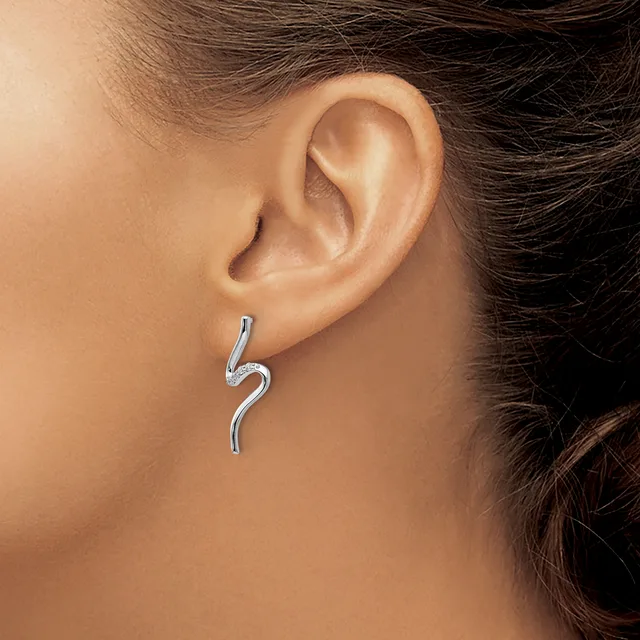 A curved silver earring with a wavy S-shape design hanging from a person's earlobe.