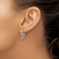 A curved silver earring with a wavy S-shape design hanging from a person's earlobe.