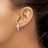 A person wearing a curved silver hoop earring in their pierced earlobe, shown in profile against their skin.