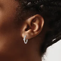 A close-up of a person's ear wearing a small silver hoop earring with a rectangular rhinestone or crystal accent at the top.