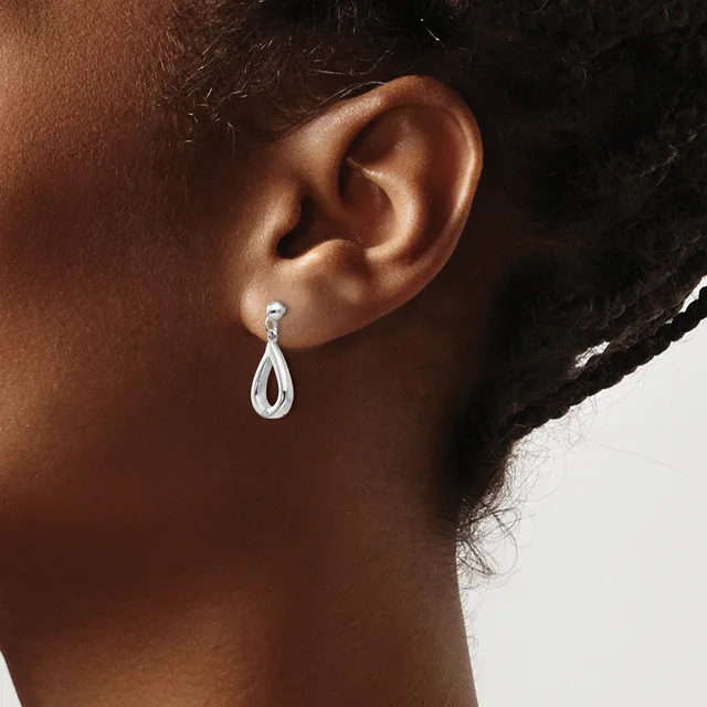 A person wearing a teardrop-shaped silver dangle earring with a small round stone at the top, shown from the side view of their ear and neck.