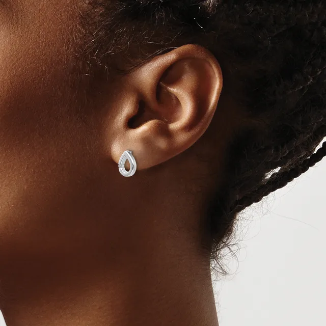 A person wearing small teardrop-shaped silver hoop earrings, shown in profile from the side of their face and neck against a neutral background.