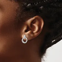 A close-up of a person's ear wearing a small silver hoop earring with a textured surface and post back.