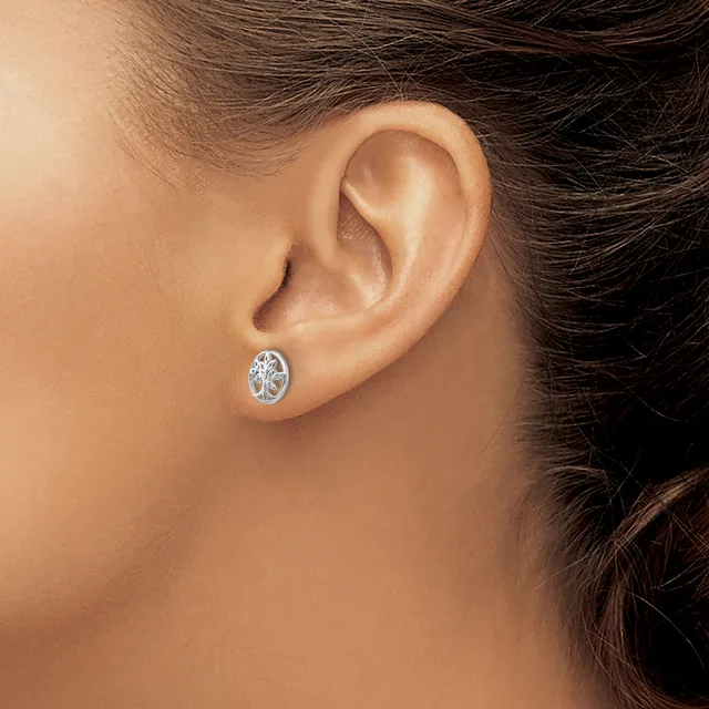A woman wearing a small oval silver earring with a decorative filigree design, shown from the side view of her ear and neck.