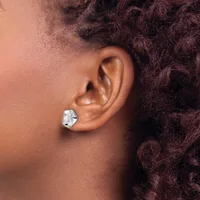 A person wearing a small silver geometric earring with an irregular polygonal shape on their earlobe, shown in profile against their shoulder.