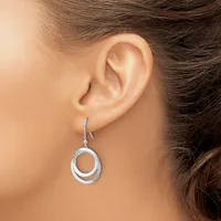 A woman wearing a silver double-circle dangle earring with a textured outer ring, shown from the side profile.