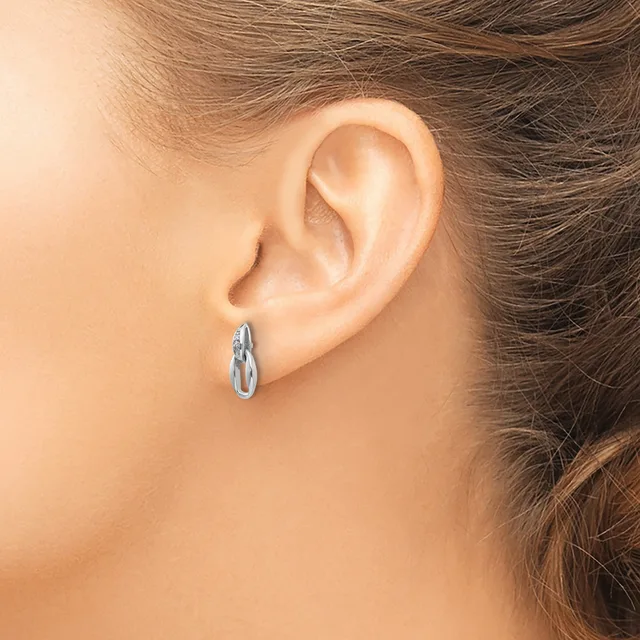 A person wearing a small twisted silver hoop earring in their earlobe, shown from the side profile view.