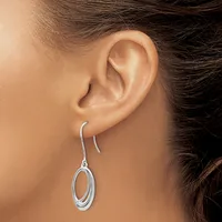 A person wearing silver oval drop earrings on wire hooks, shown from the side profile with brown hair pulled back.