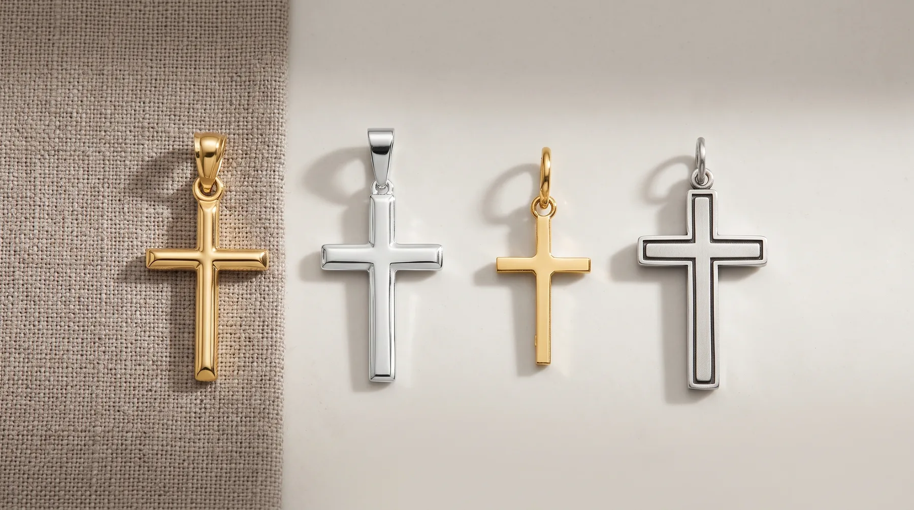 Four cross pendants in gold and silver finishes arranged in a row on a neutral background, displayed with shadows.