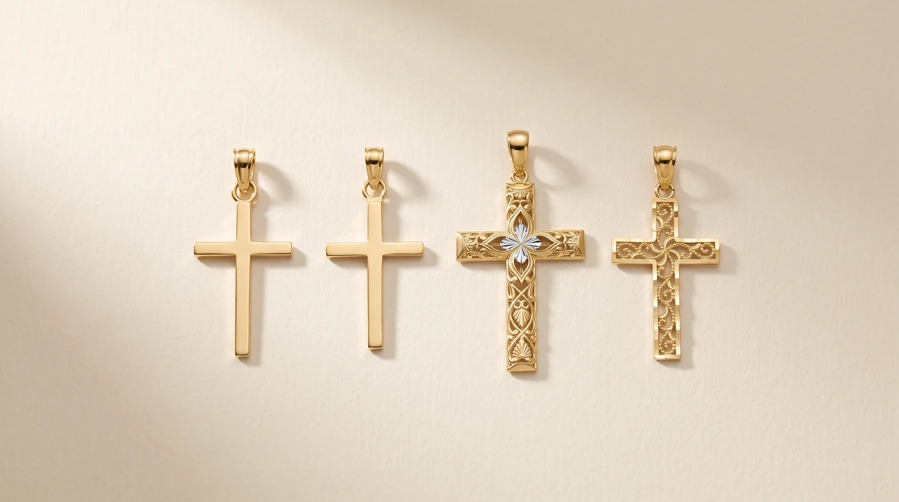 Four gold cross pendants arranged in a row, two plain polished crosses on the left and two ornate textured crosses on the right, one featuring a small diamond or crystal stone.