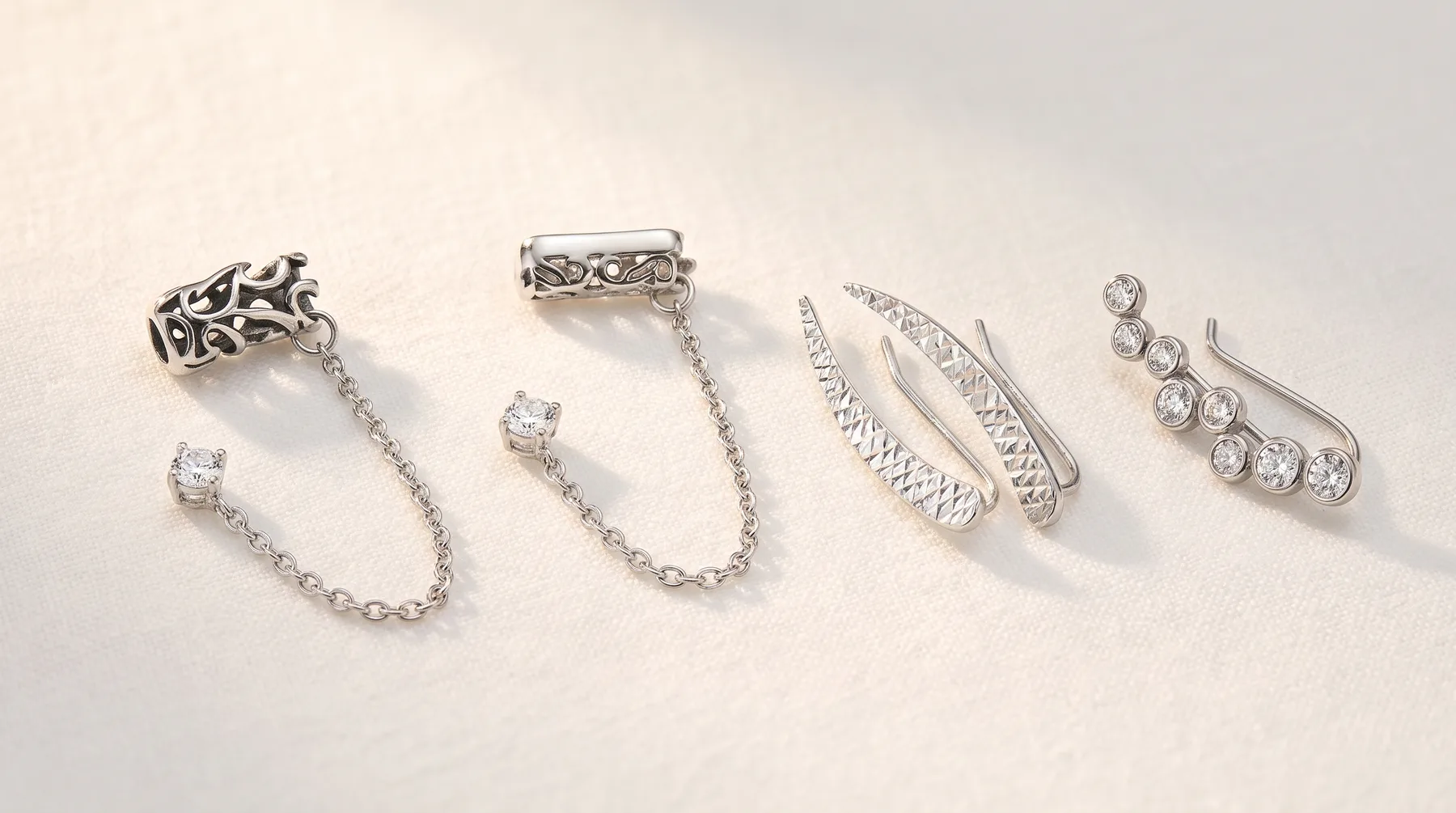 Six silver ear cuffs and connectors arranged in a row, featuring various designs including filigree patterns, chain links, and cubic zirconia stone details.