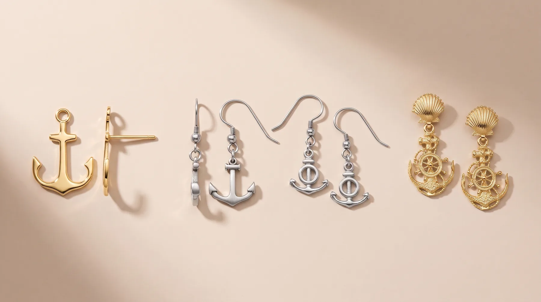 Six pairs of nautical-themed earrings displayed on a beige surface, including gold anchor studs, gold crossed anchors, silver anchor drops, silver anchor drops with small beads, and gold ship wheel drops with shell-shaped tops.