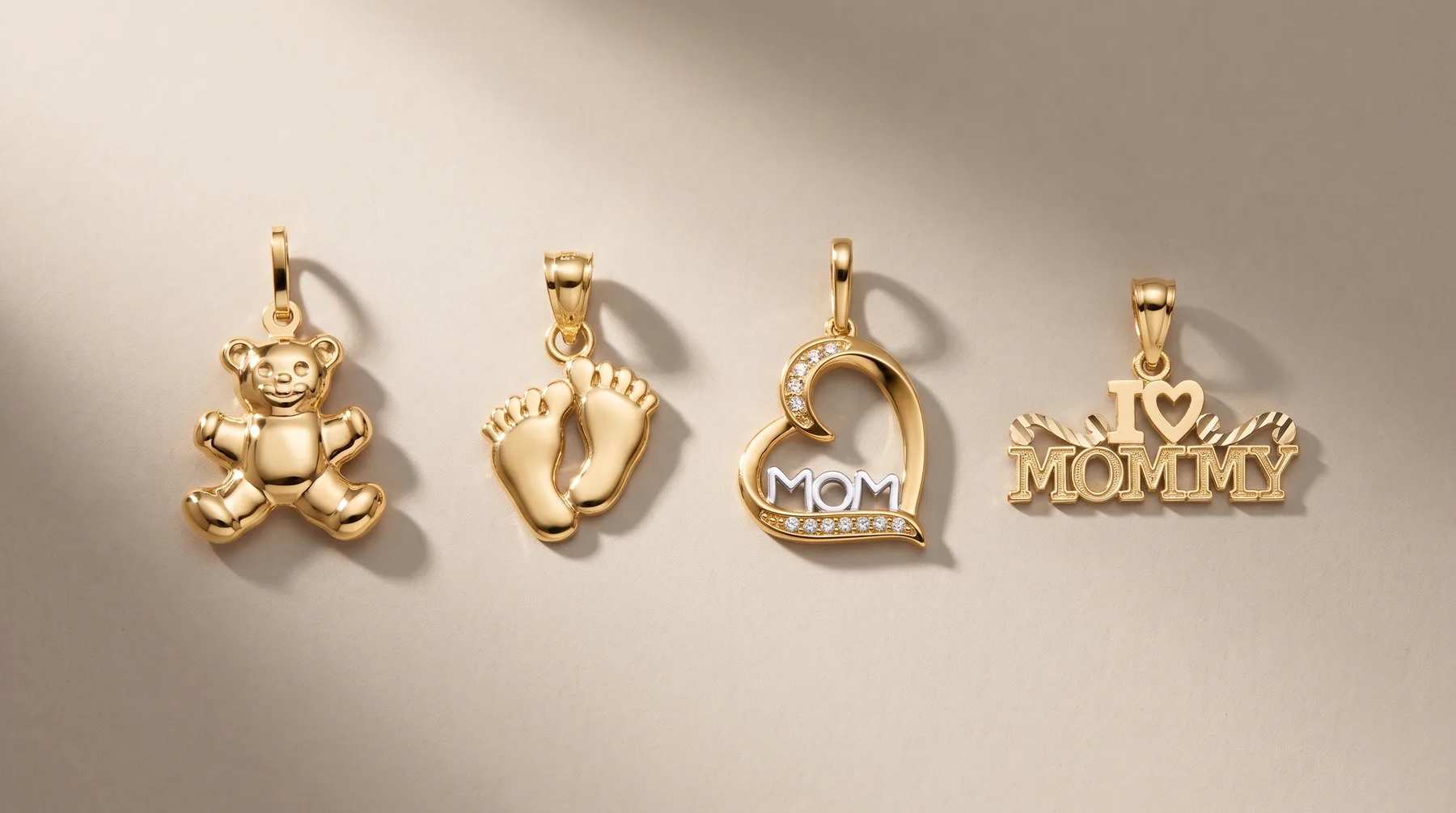 Four gold pendants arranged in a row: a teddy bear, baby footprints, a heart with "MOM" text, and "MOMMY" lettering, each with a small hallmark.