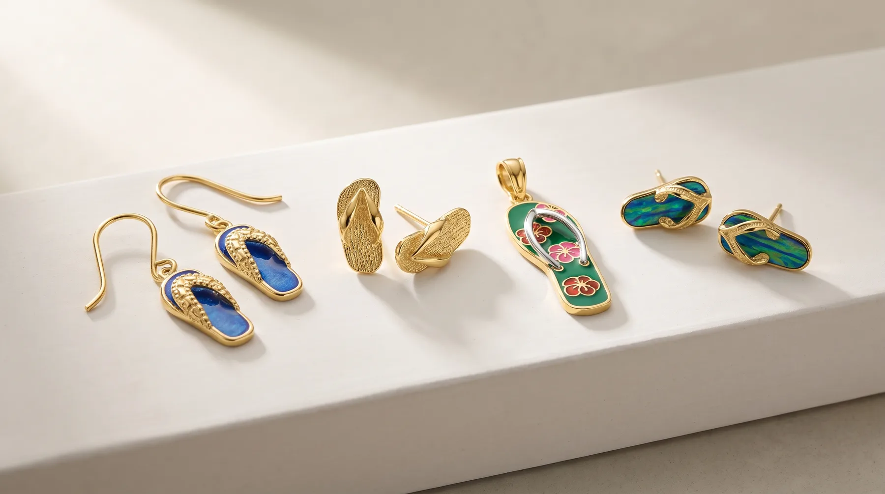 Five pairs of gold-toned jewelry with gemstones arranged on a white surface, including blue stone earrings, plain gold earrings, a colorful pendant with matching earrings, and teal stone earrings.