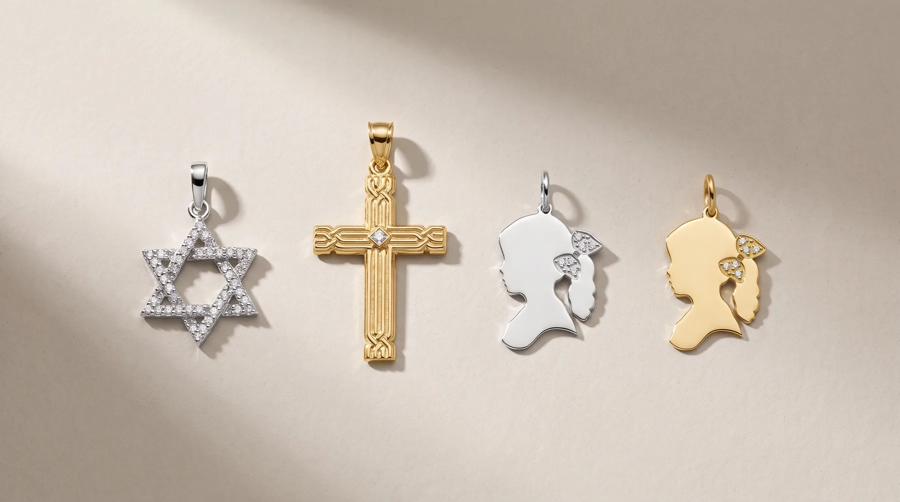 Four metal pendants arranged in a row on a neutral surface: a silver star with crystal stones, a gold cross with textured details, a silver silhouette profile, and a gold silhouette profile.