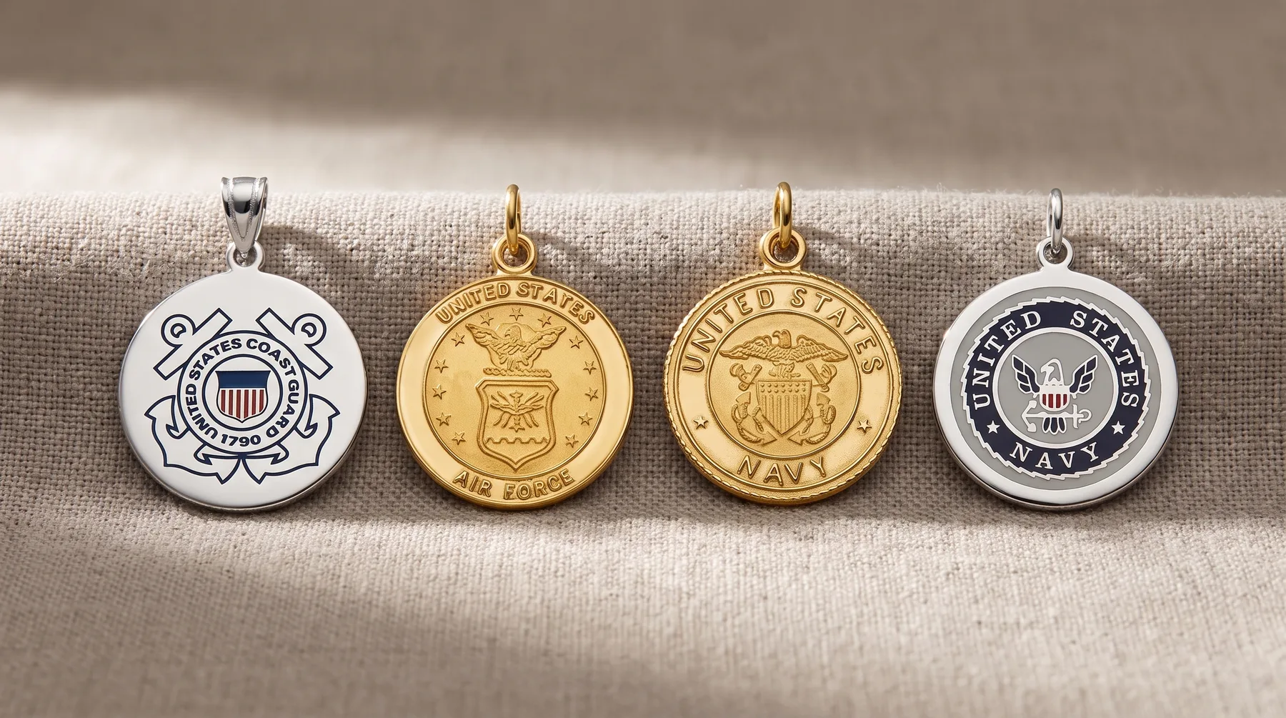 Four military service branch pendants hung on a beige fabric, including silver and gold-toned circular medallions with eagles and heraldic emblems.