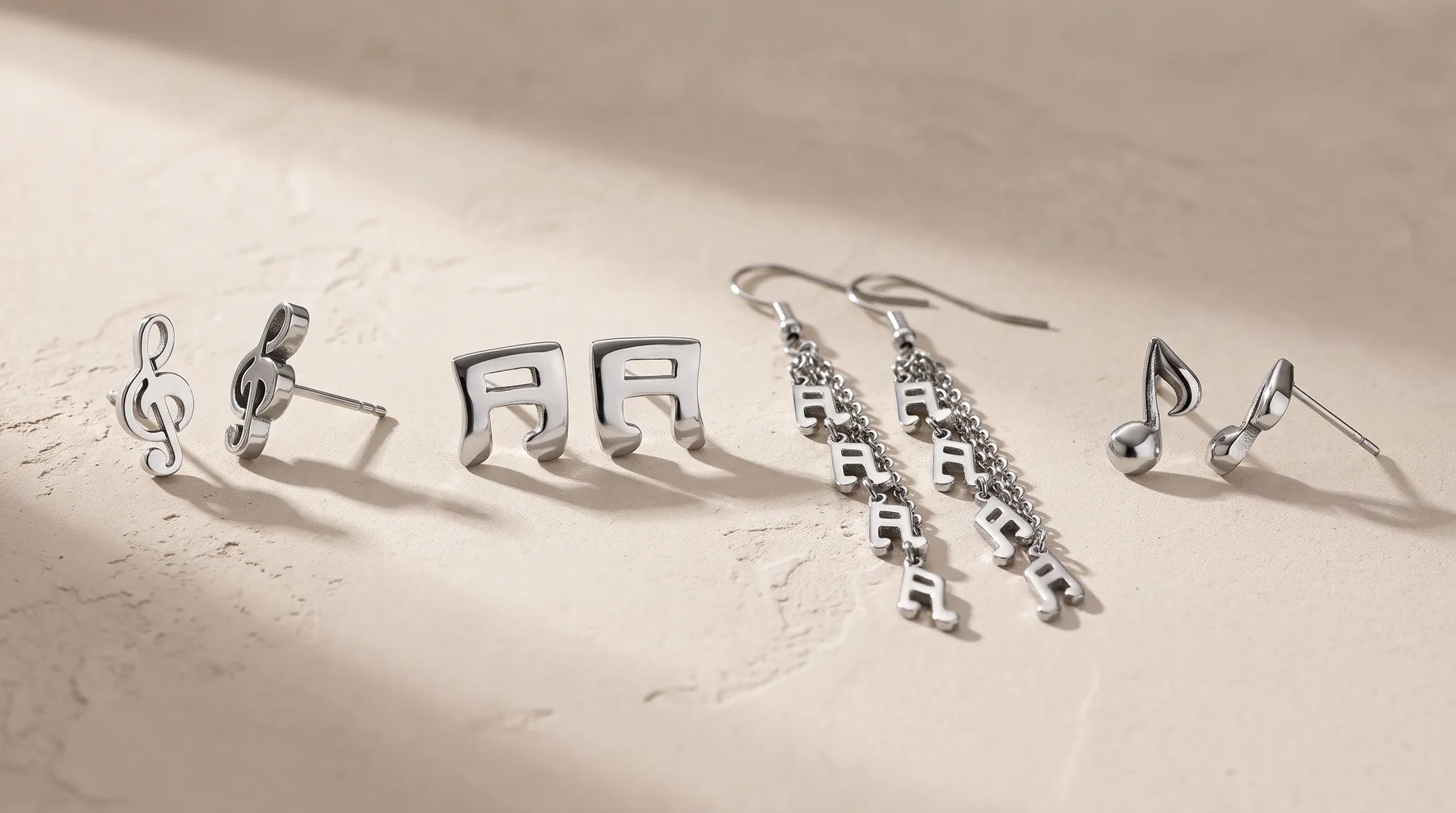 Silver musical note jewelry arranged in a line on a white surface, including treble clef studs, eighth note studs, beaded drop earrings, and musical note stud earrings.